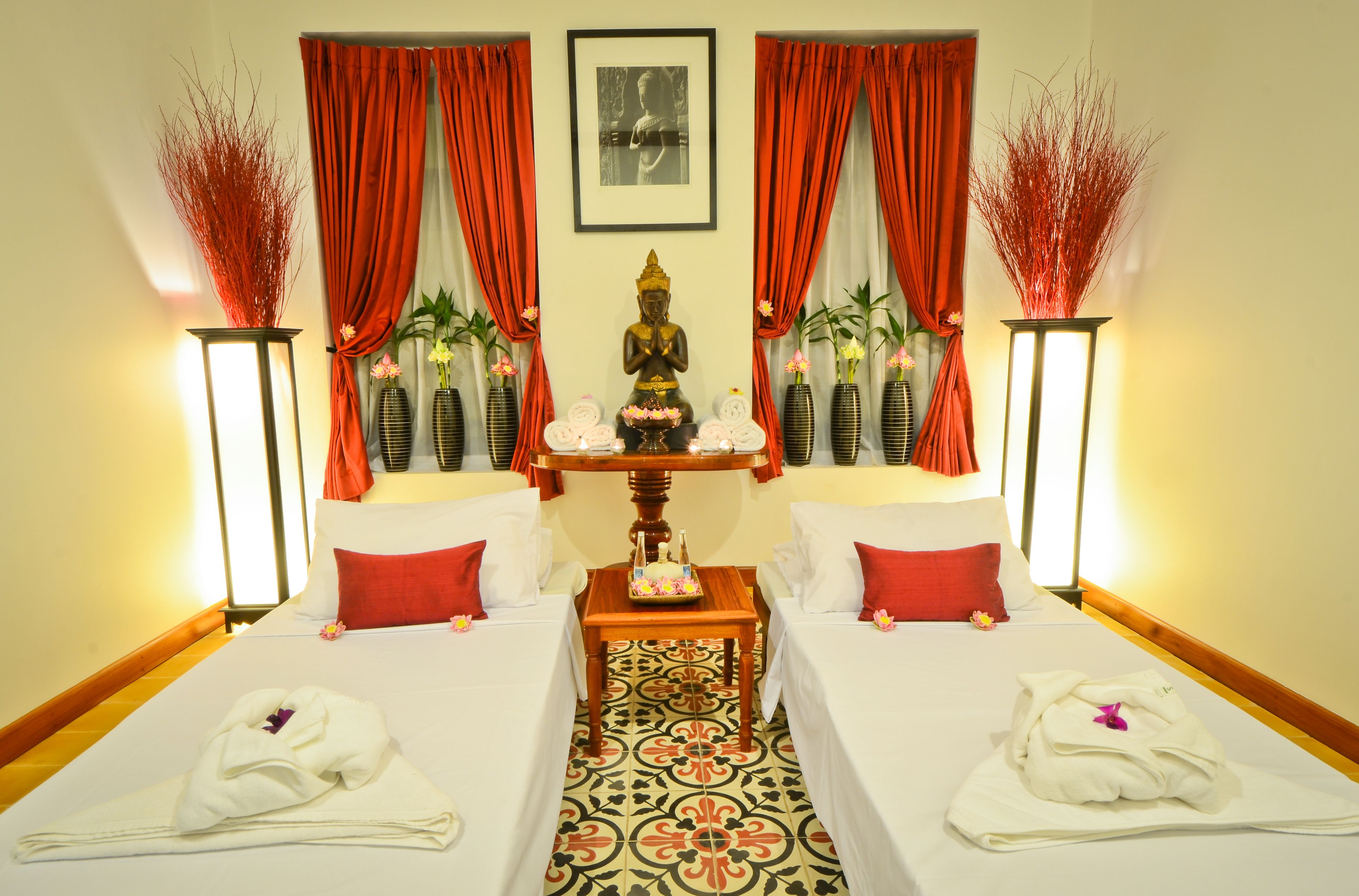 Une chambre d’hôtel avec deux lits, une statue et une table sur laquelle se trouve un plateau de fleurs.