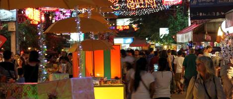A busy street market with people walking and stalls selling goods.