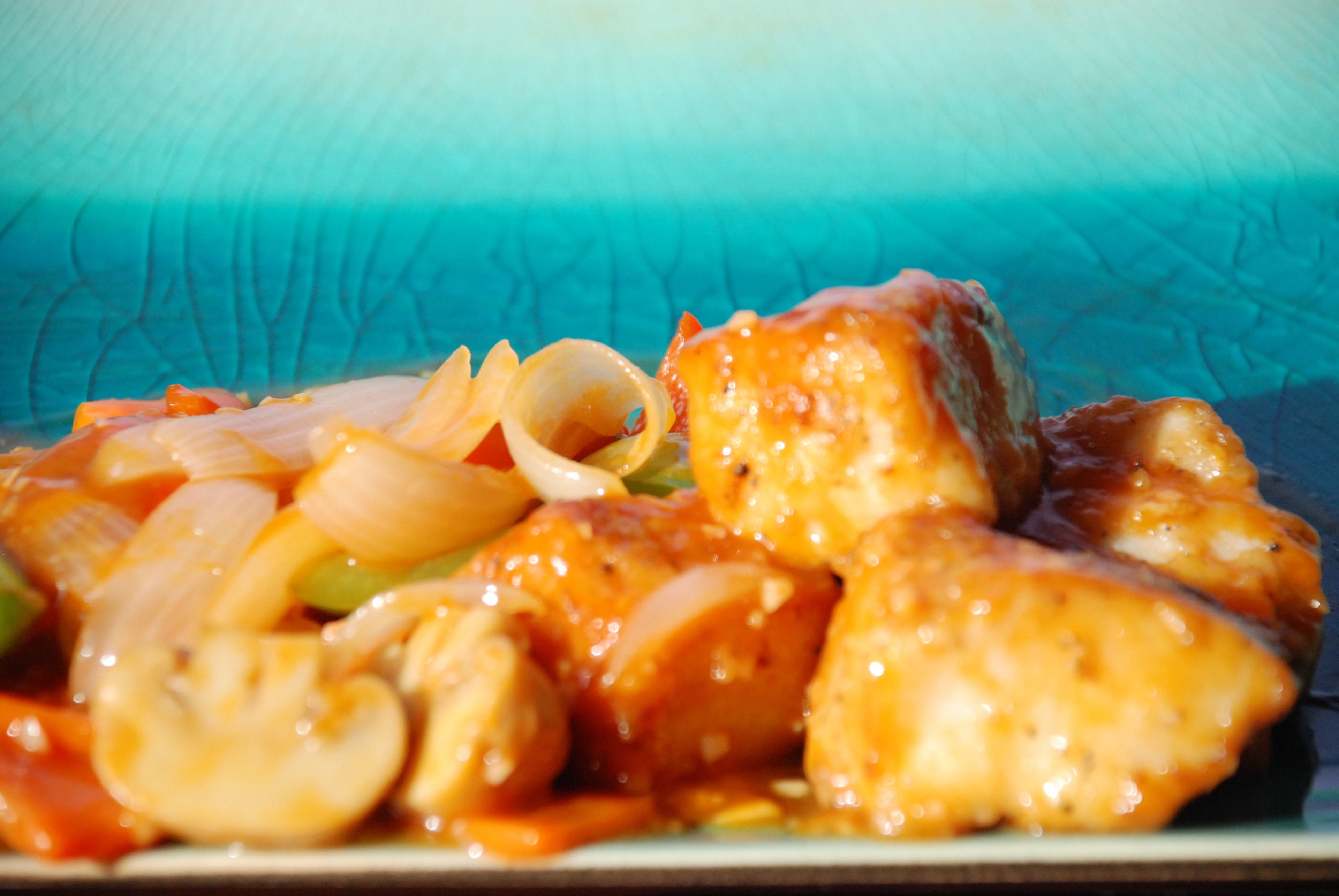 Primer plano de un plato con pollo, champiñones y cebollas en salsa.