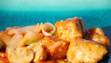 Primer plano de un plato con pollo, champiñones y cebollas en salsa.