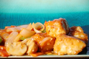 Primer plano de un plato con pollo, champiñones y cebollas en salsa.