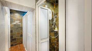 A bathroom with a shower, tiled walls, and a tiled floor.