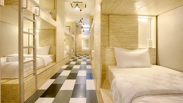 A hotel room with bunk beds, a checkered floor, and a bed with a white bedspread. - the youniQ Hotel (Sepang)