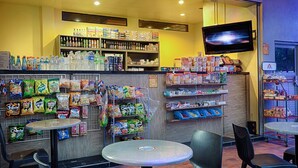 A snack kiosk with various packaged snacks and beverages, a television screen, and seating areas. - the youniQ Hotel (Sepang)