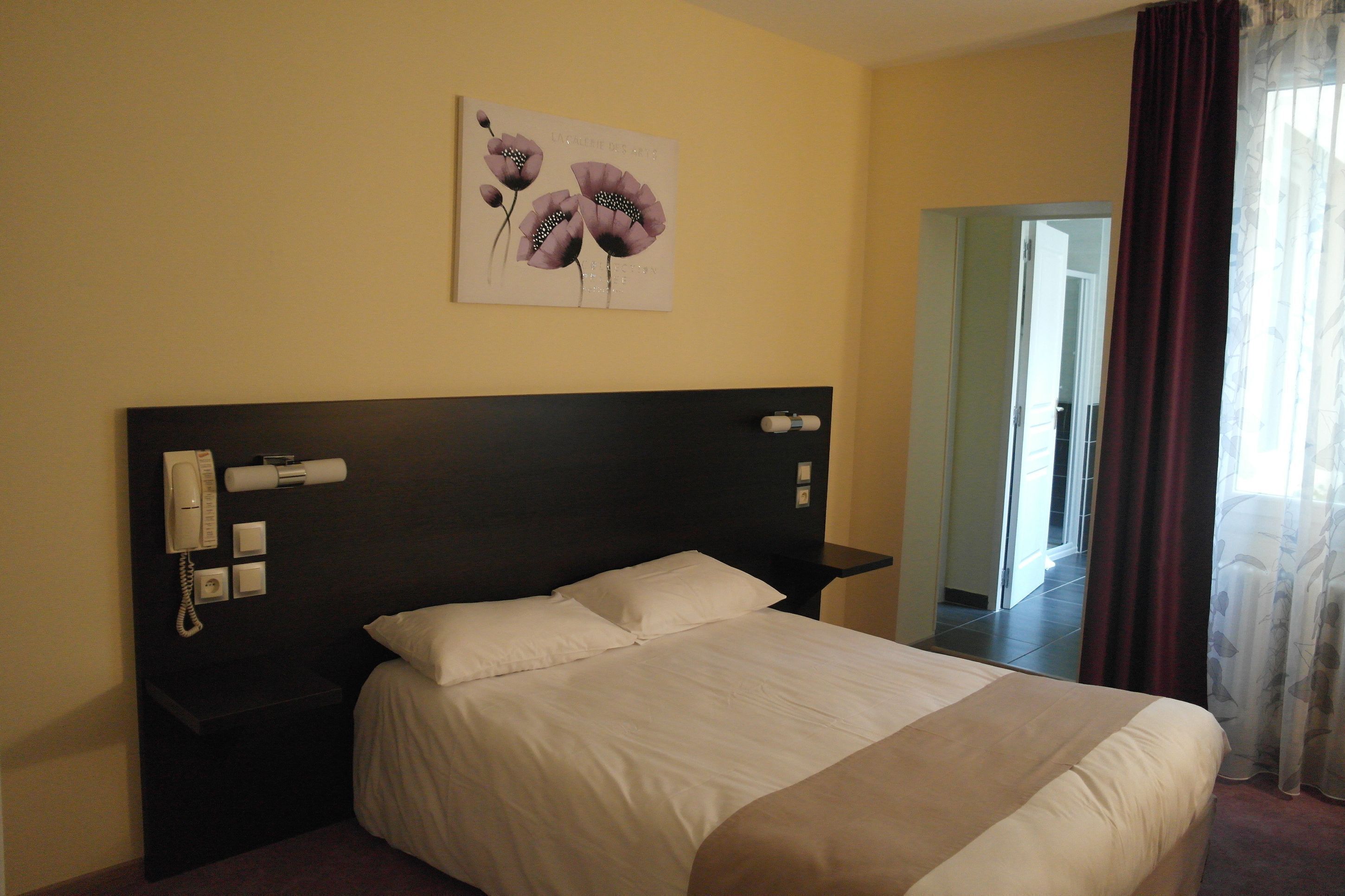 Una habitación de hotel con una cama grande, un teléfono en la mesita de noche y un cuadro en la pared.