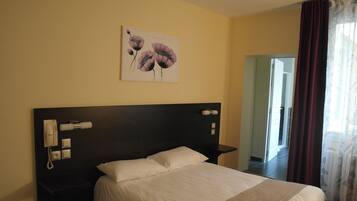 Una habitación de hotel con una cama grande, un teléfono en la mesita de noche y un cuadro en la pared.