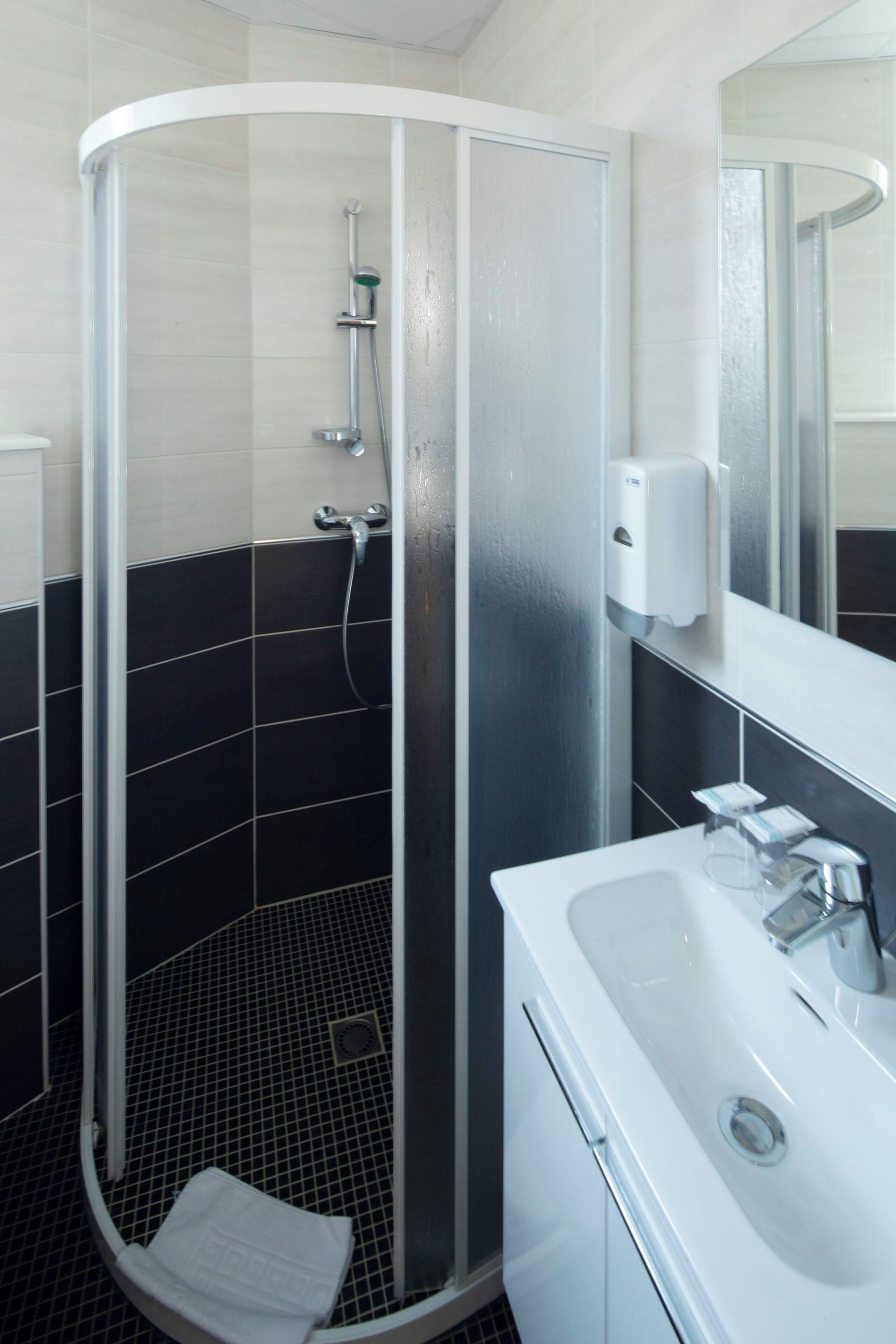 A modern bathroom with a glass-enclosed shower, a white sink, and a mirror.