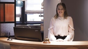 Un comptoir d’accueil au design moderne, doté d’un plan de travail en bois, d’un téléphone et d’une cloche.