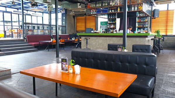 Un restaurant doté d’un bar, de différents types de tables et de chaises, ainsi que d’un comptoir où sont exposées diverses bouteilles.