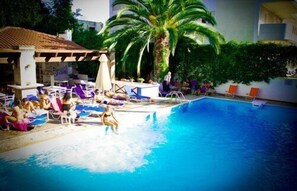 A swimming pool with lounge chairs and a palm tree. - Green Hill Hotel (Irakleio)
