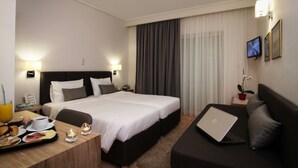 Una habitación de hotel con una cama doble, un escritorio con productos para el desayuno, una computadora portátil y un televisor en la pared.