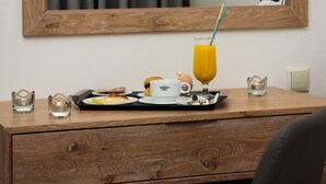 Escritorio de madera con una bandeja de alimentos para el desayuno, un vaso de jugo de naranja y una taza con pajita.