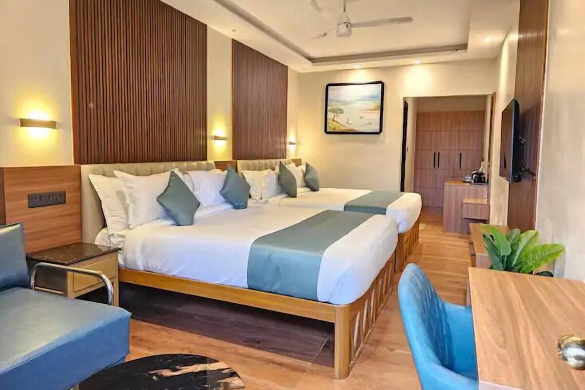 Une chambre d’hôtel avec un grand lit, un bureau, une chaise, une télévision et un ventilateur de plafond.