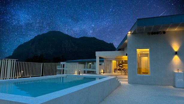 A modern building with a pool and a mountain backdrop under a starry sky. - Y Resort Jeju (Seogwipo)