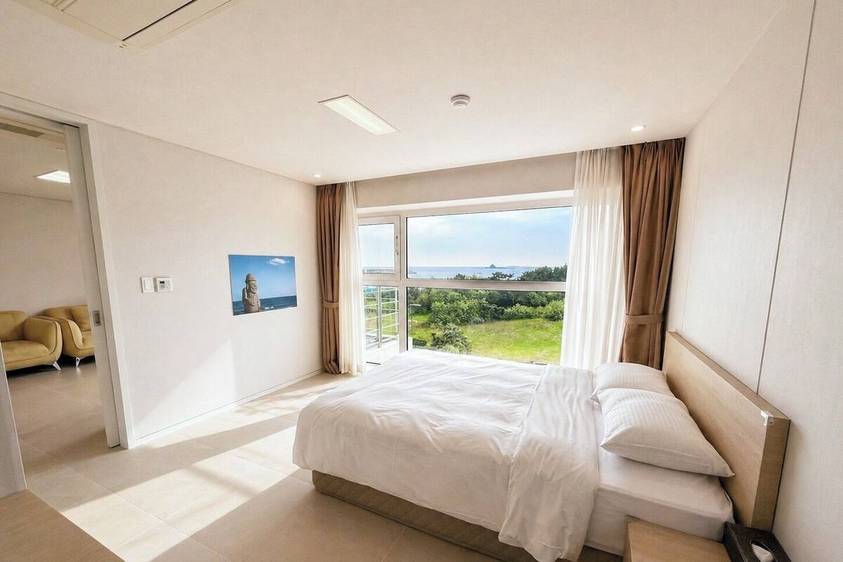 A hotel room with a large bed, a view of the sea, and a balcony.
