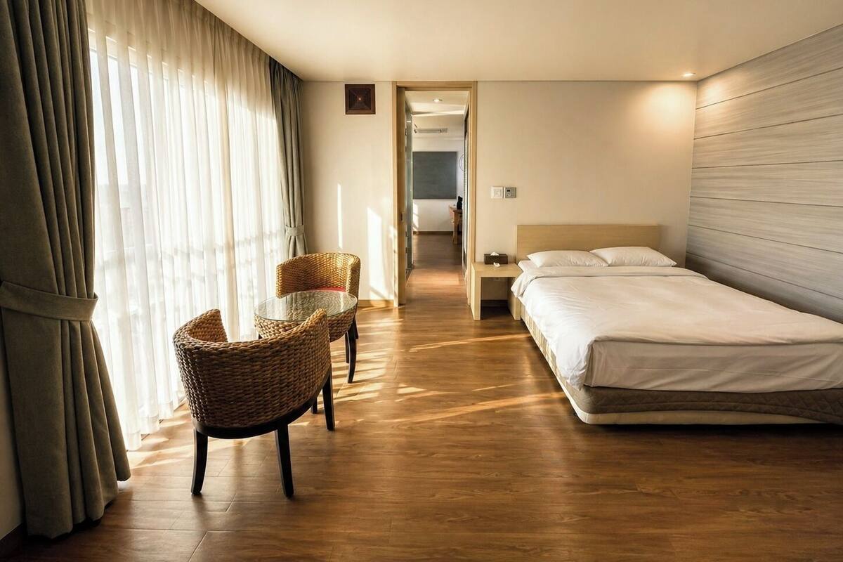 A hotel room with a bed, a chair, a nightstand, and a view of the hallway.