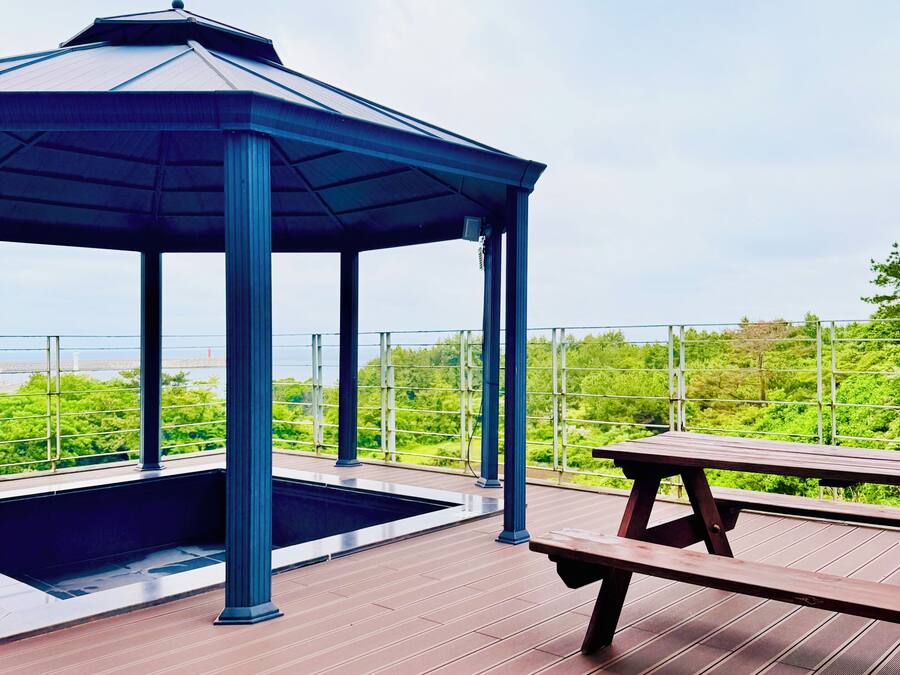 Ein Pavillon mit Pool, Picknicktisch und Blick auf Grünflächen und ein Gewässer.