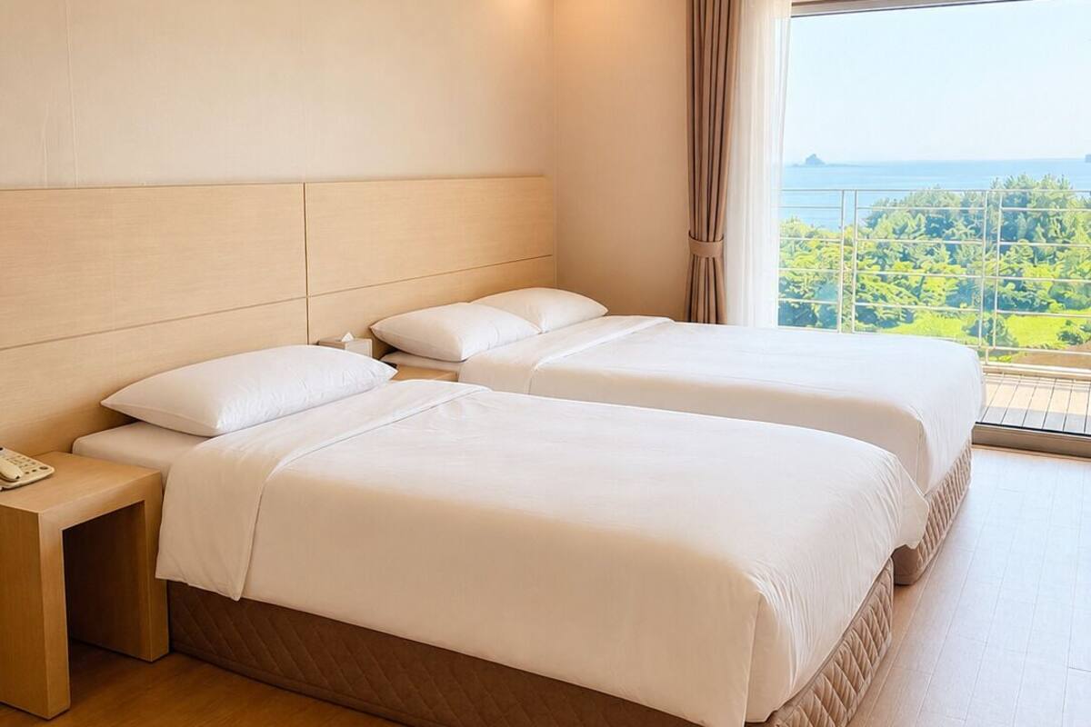 A hotel room with two beds, a nightstand, a phone, and a large window with a view.