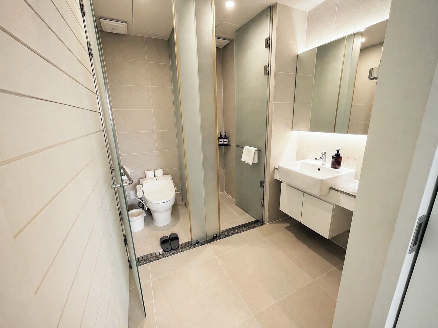 Ein modernes Badezimmer mit Toilette, Waschbecken und Duschkabine aus Glas.
