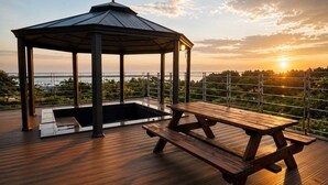 A wooden deck with a gazebo and picnic table overlooking a body of water. - Y Resort Jeju (Seogwipo)