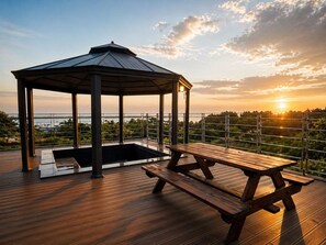 A wooden deck with a gazebo and picnic table overlooking a body of water. - Y Resort Jeju (Seogwipo)