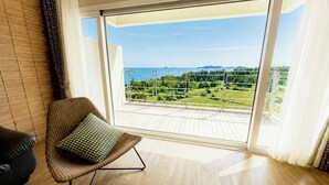 A balcony with a view of a green landscape and the sea. - Y Resort Jeju (Seogwipo)