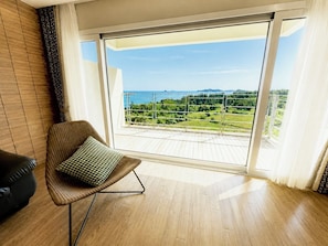 A balcony with a view of a green landscape and the sea. - Y Resort Jeju (Seogwipo)