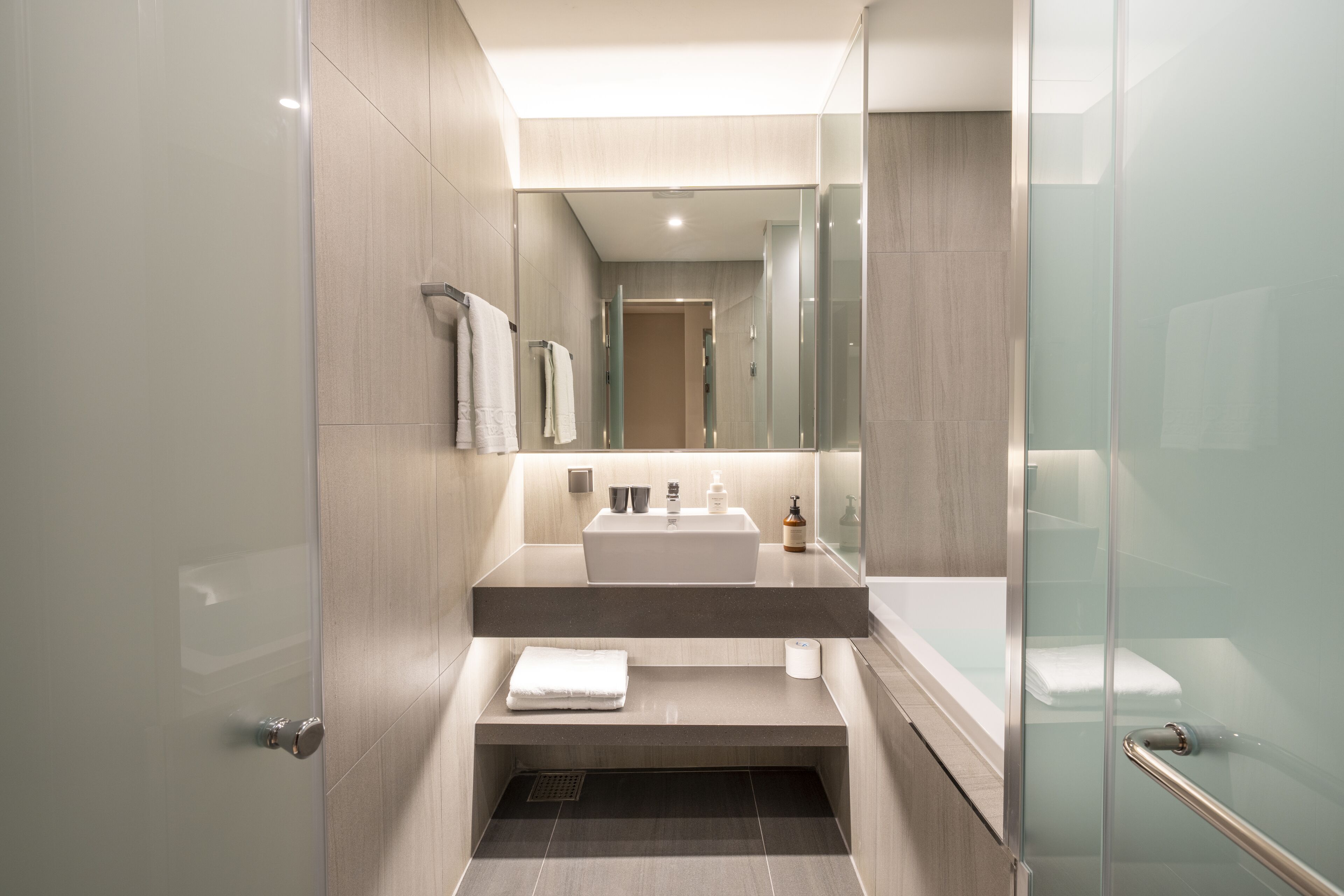 A modern bathroom with a glass shower enclosure, a sink with a mirror, and a towel rack.