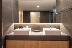 Un baño moderno con dos lavamanos, un espejo y un armario de madera.
