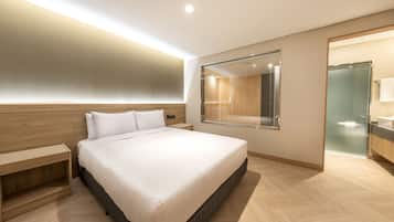 Ein modernes Schlafzimmer mit einem großen Bett, einem Holzkopfende, Nachttischen und einer Duschkabine aus Glas.