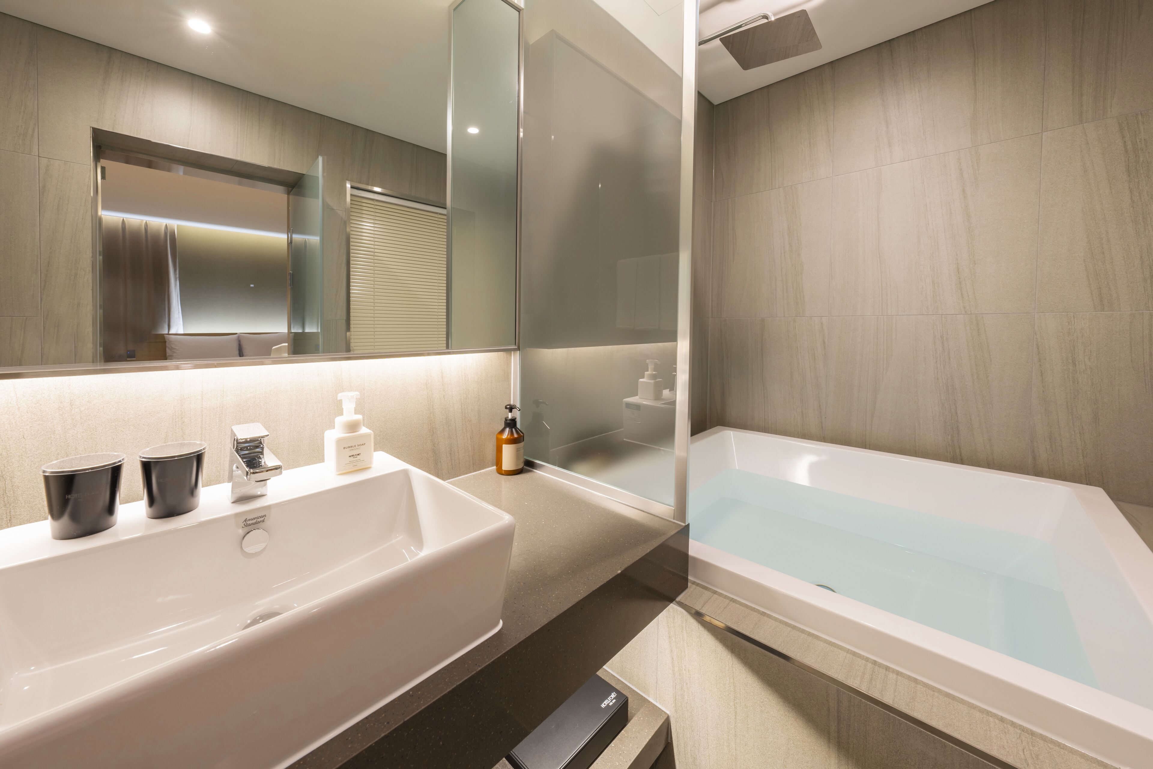 A modern bathroom with a large white bathtub, a sink with a mirror, and a shower area.