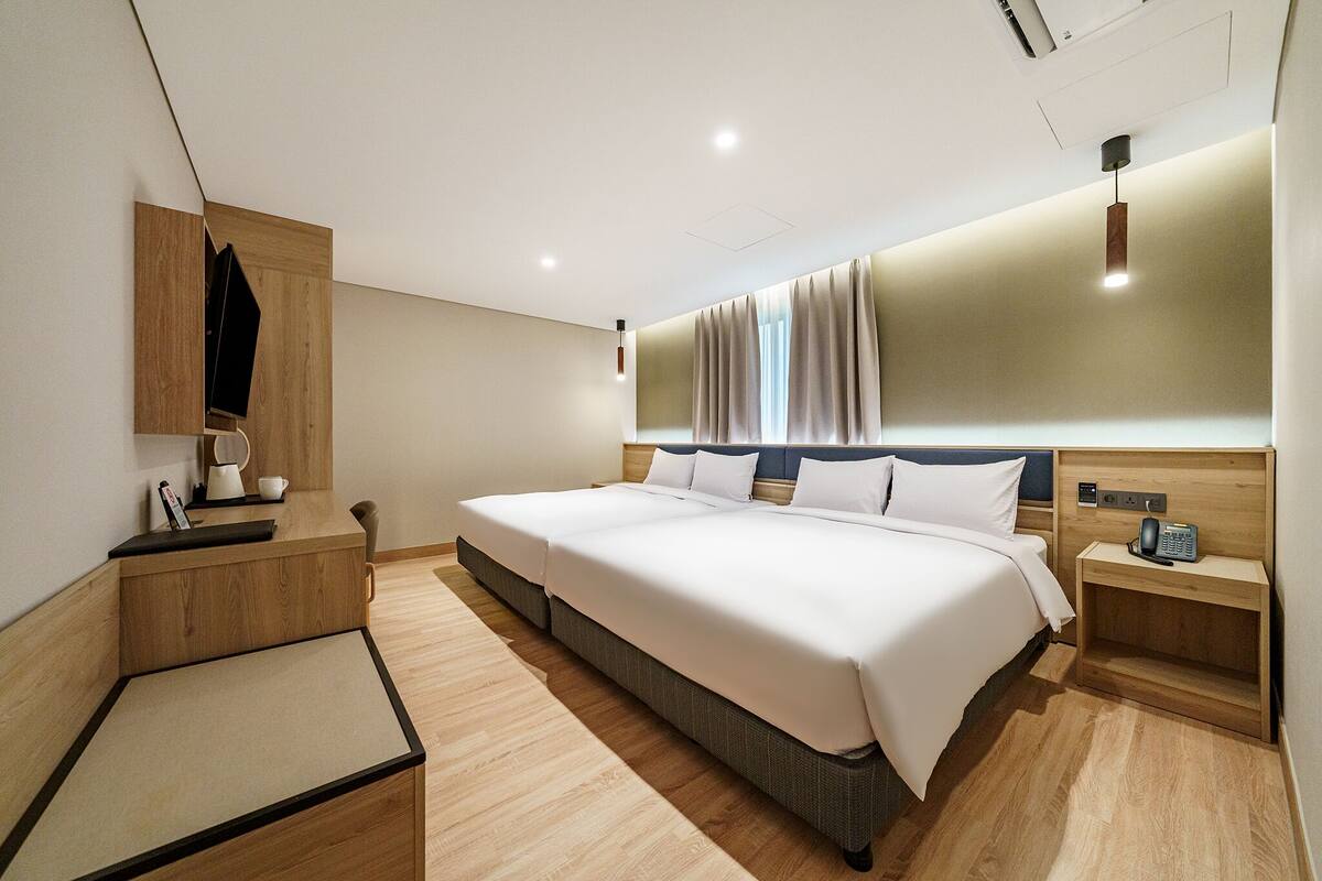 Ein modernes Hotelzimmer mit einem großen Bett, Nachttischen, einem Spiegel und einer eingebauten Ablagefläche.