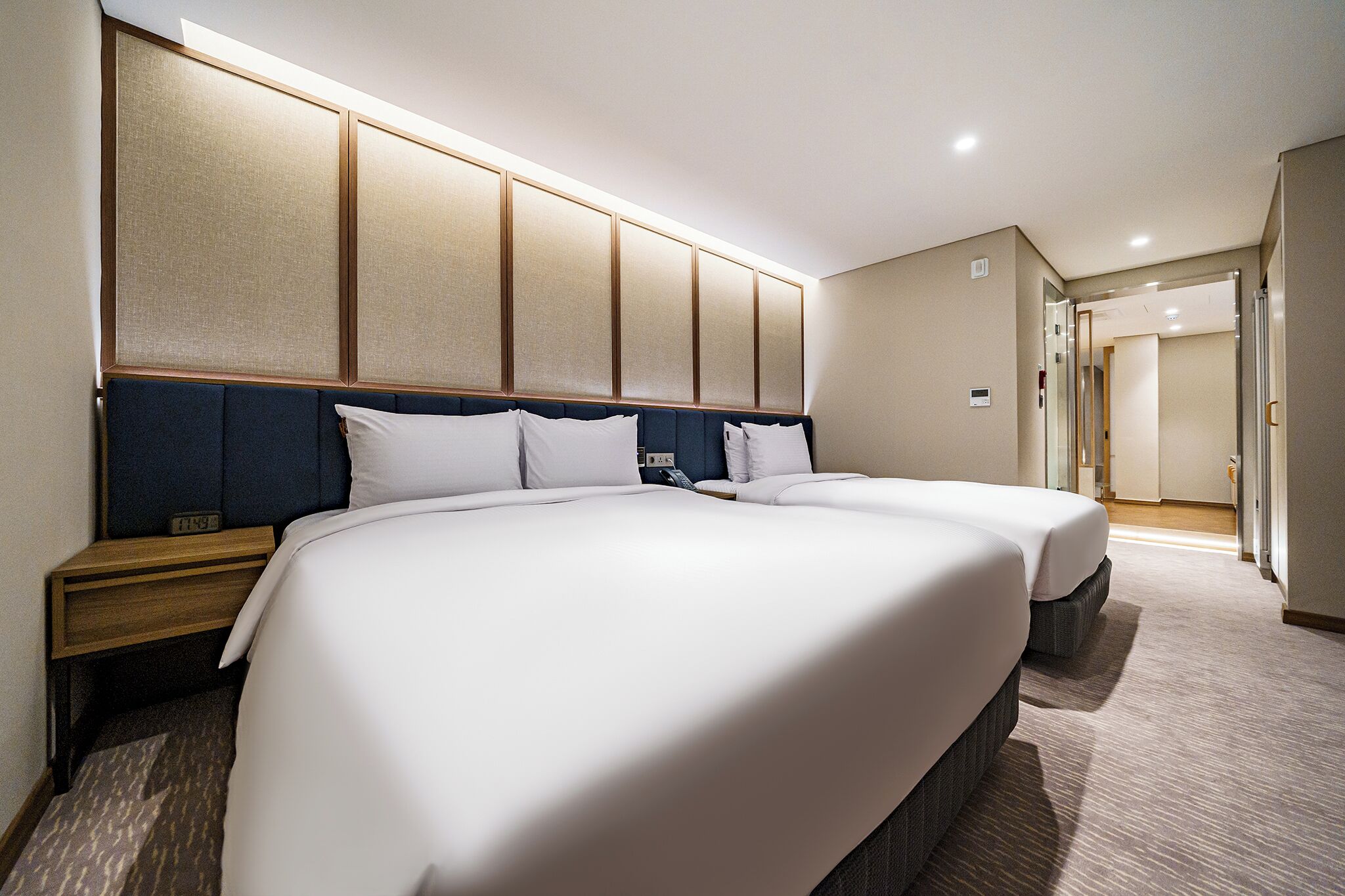 A hotel room with two beds, a wooden headboard, and a carpeted floor.