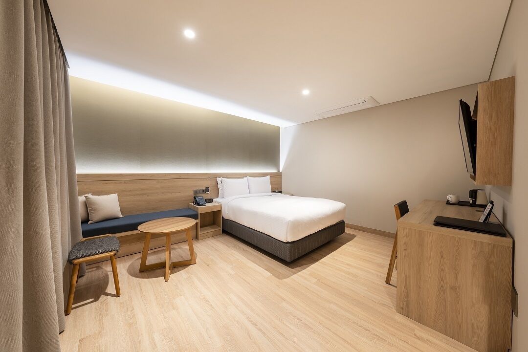 Habitació d'hotel moderna amb llit, taula de nit, cadira i escriptori amb cadira.
