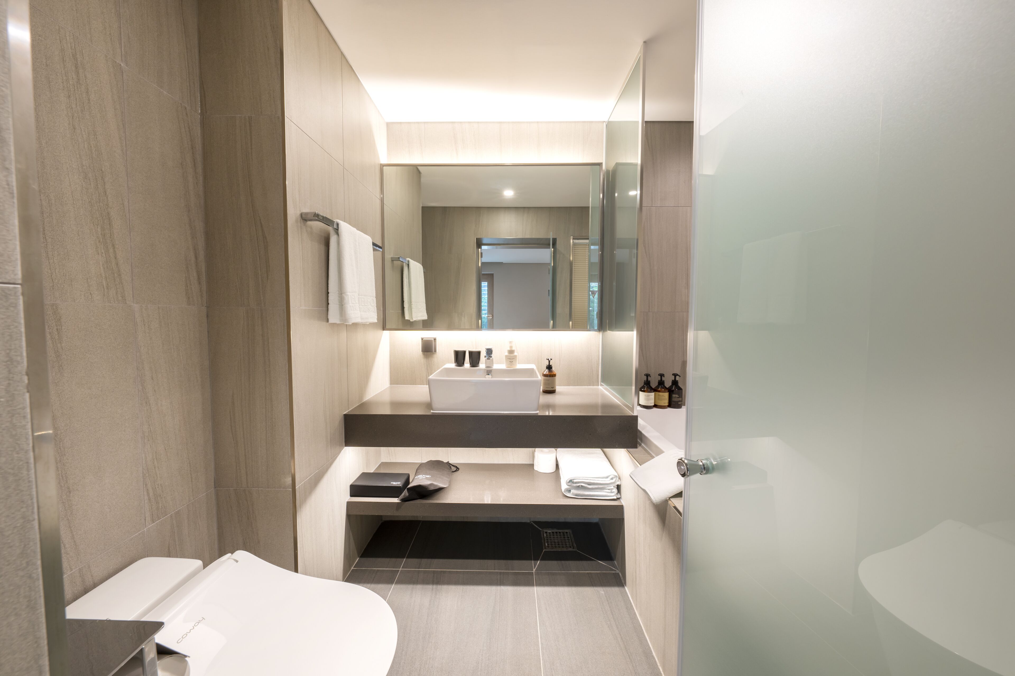 Une salle de bain moderne avec un grand miroir, une baignoire et des toilettes.