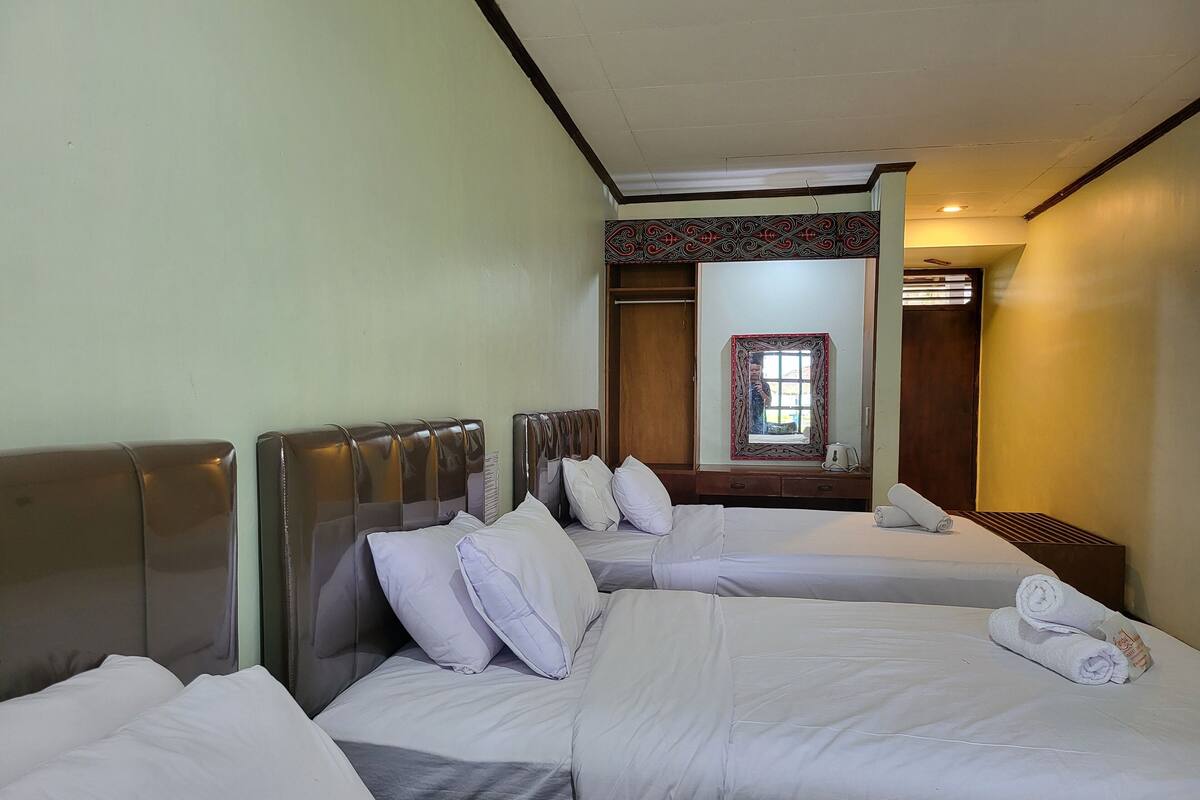 A hotel room with two beds, a wooden headboard, a mirror, and a window with a view.