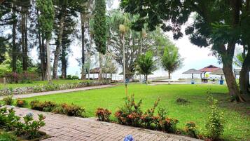 A well-maintained garden with a paved walkway, a gazebo, and a view of the sea.