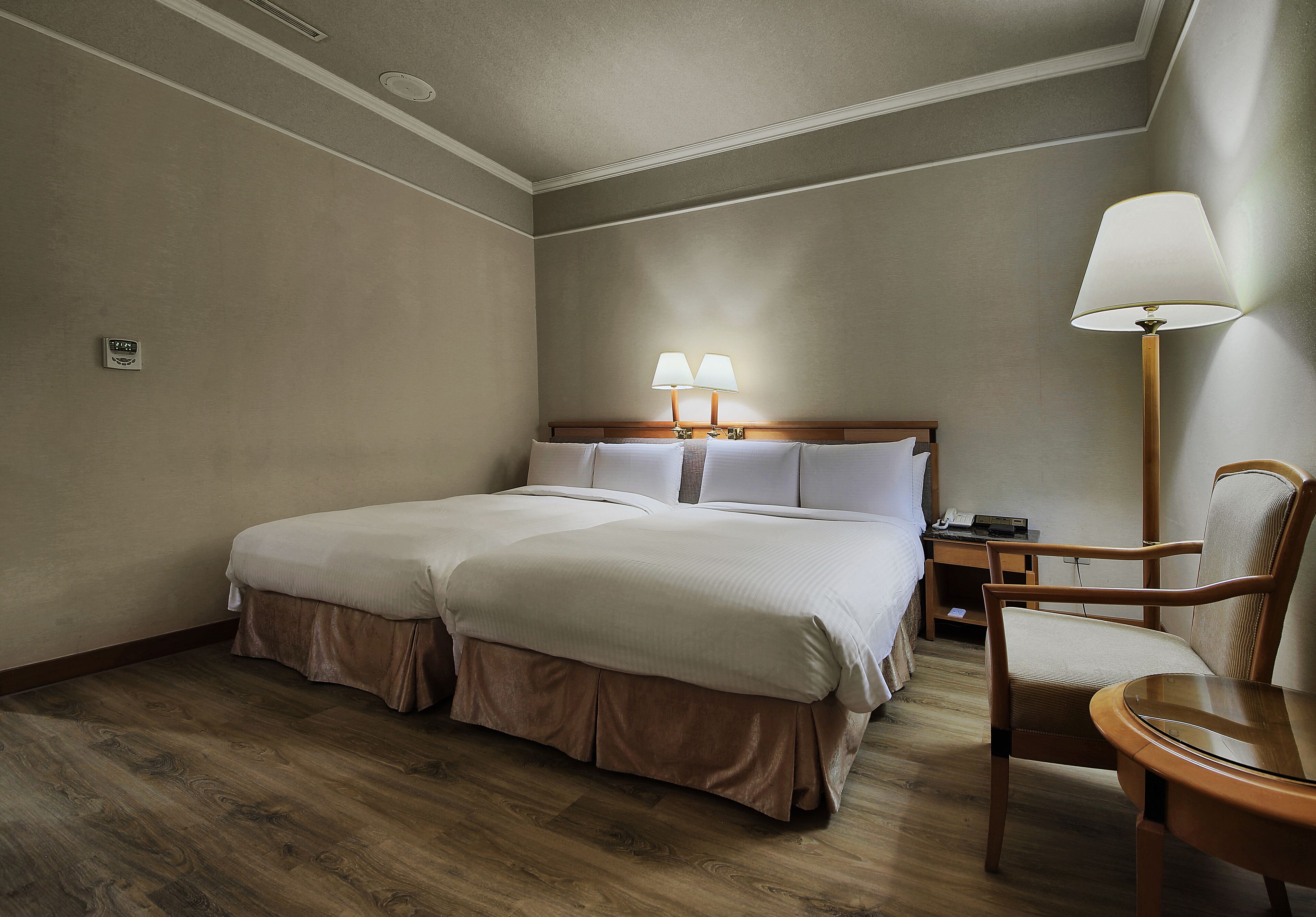 A hotel room with a double bed, a bedside table, a chair, and a lamp.