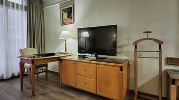 A hotel room with a wooden desk, a television, a lamp, and a chair.