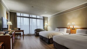 Una habitación de hotel con dos camas, un escritorio, una silla y un televisor.