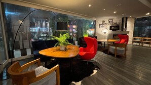 Una sala de estar moderna con una mesa redonda de madera, una planta en maceta, un sillón rojo y una alfombra blanco y negro.