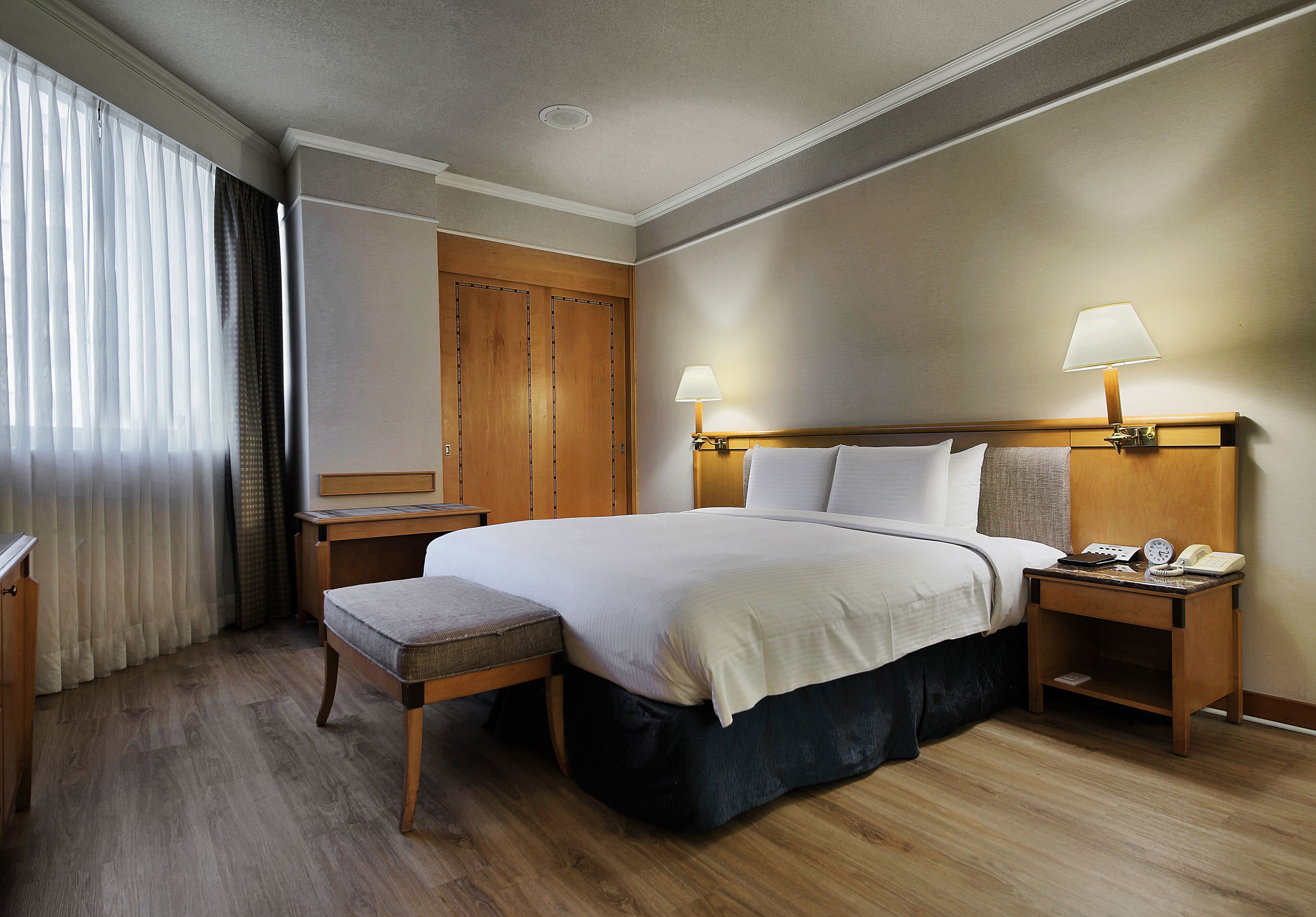 A hotel room with a large bed, bedside tables, a desk, and a chair.