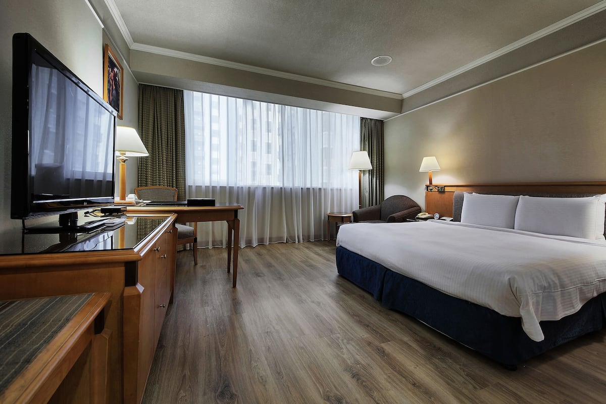 A hotel room with a bed, a desk, a television, and two lamps.