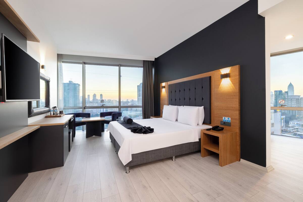Una habitación de hotel moderna con una cama grande, un escritorio y vistas al horizonte de la ciudad.