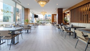 A modern hotel lobby with a chandelier, seating areas, and large windows.