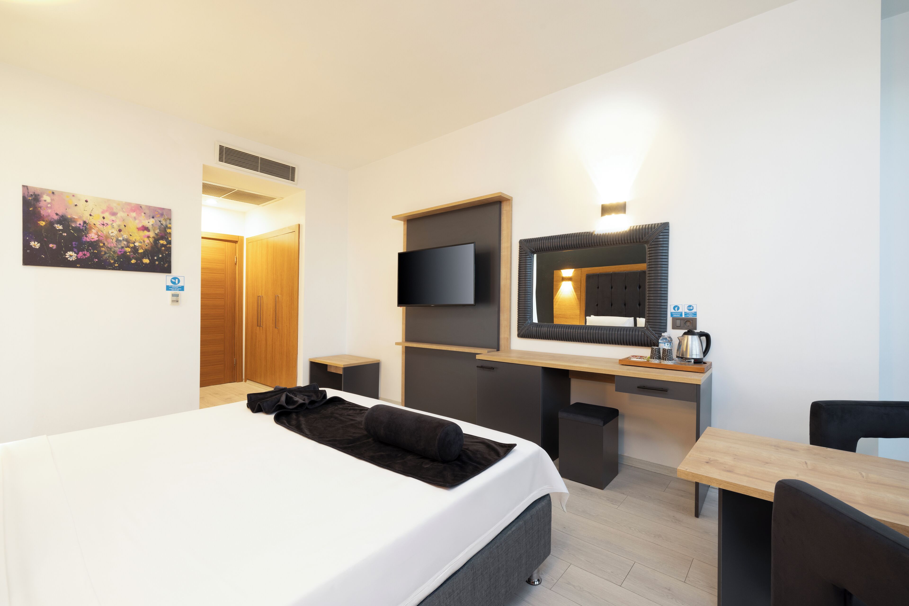 Ein Hotelzimmer mit Bett, Schreibtisch, Fernseher und Spiegel.