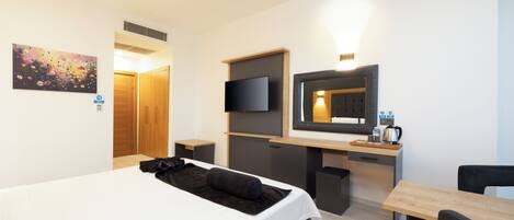 Ein Hotelzimmer mit Bett, Schreibtisch, Fernseher und Spiegel.