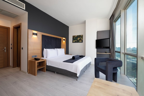 Une chambre d’hôtel moderne dotée d’un grand lit, d’un bureau, d’une chaise, d’une télévision et offrant une vue sur la ville.