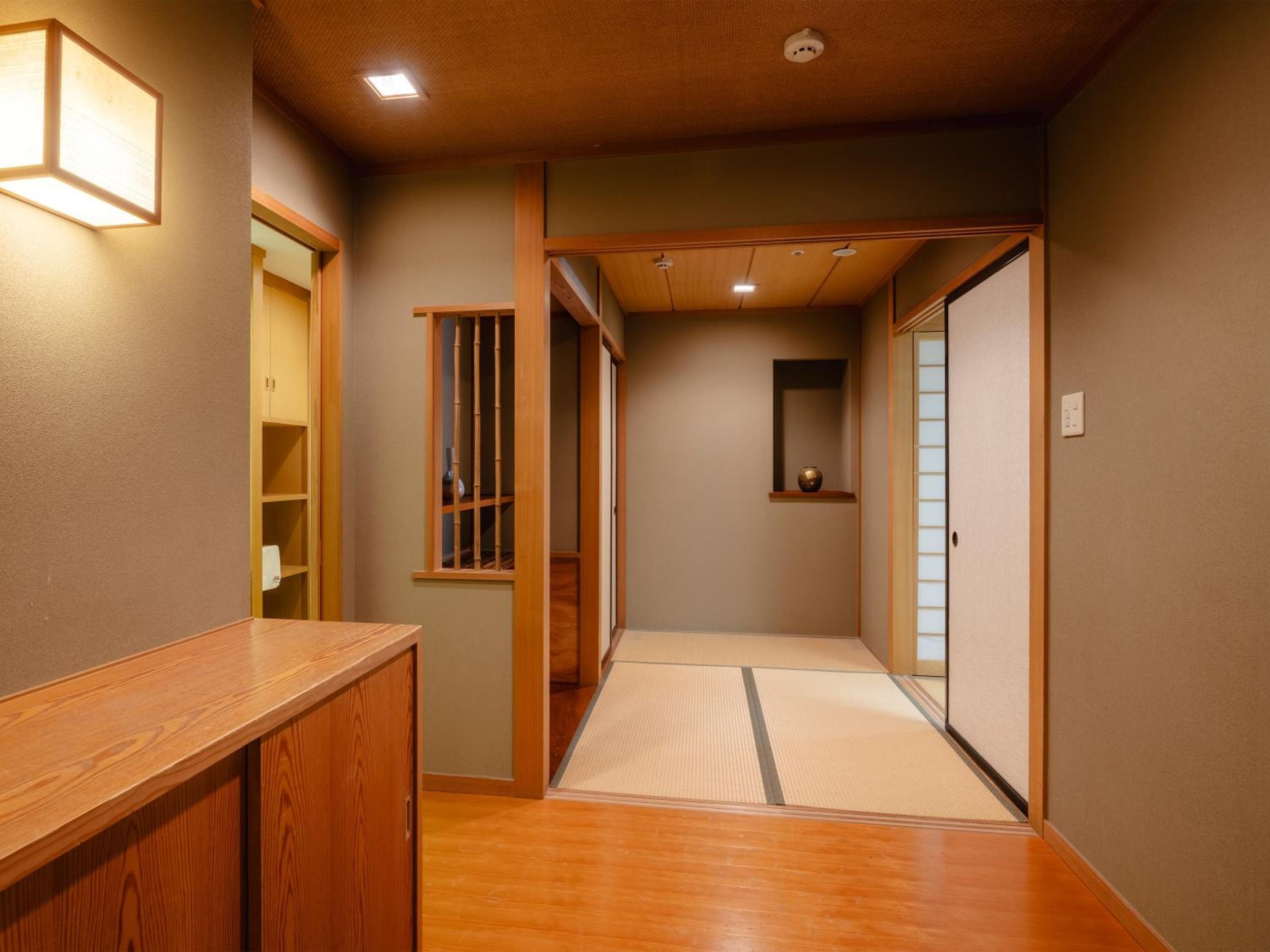 A hallway with wooden flooring, a wooden counter, a sliding door, and a small shelf with a decorative item.