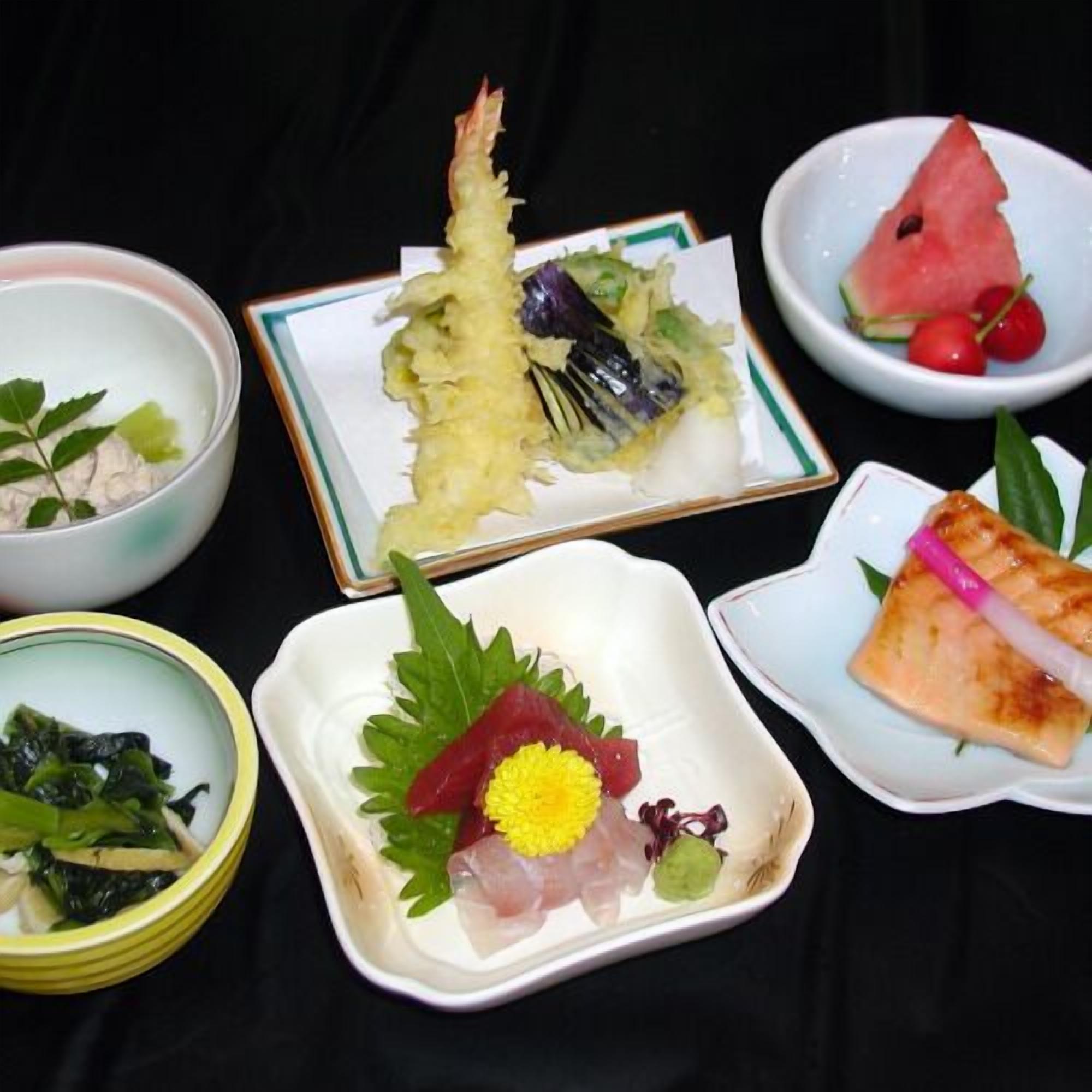 Forskellige japanske retter, heriblandt sashimi, tempura og en skål suppe.